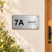 Scandinavisch huisnummerbord met naam aan de muur met vier schroeven