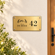 Landelijk huisnummerbord met naam aan de muur met vier schroeven